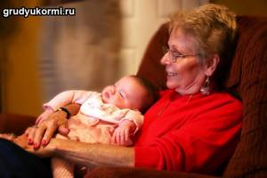Бабушка сидит на кресле с грудным внучком