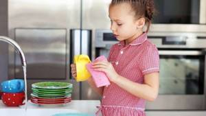 Девочка 5 лет моет посуду в раковине