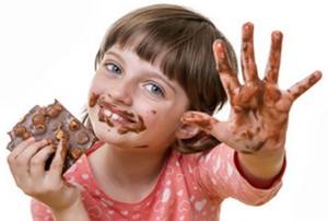 Девочка ест шоколад с орехами