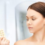 Грустная девушка держит в руках таблетки