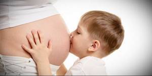 Мальчик целует живот беременной мамы