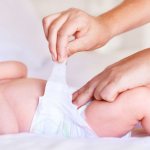 Мама одевает ребенка в подгузник