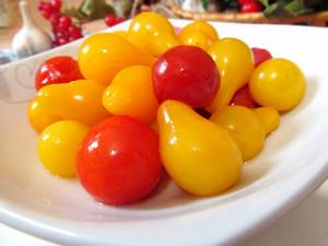 Маринованные красные и желтые помидоры на белой тарелке