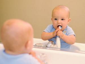 Веселая чистка зубов перед зеркалом с малышом
