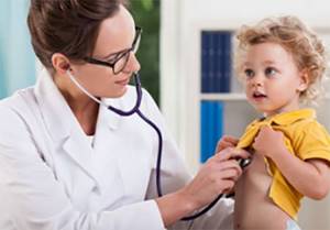 Врач фонендоскопом прослушивает ребенку грудь