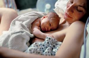 Женщина держит на руках новорожденного ребенка
